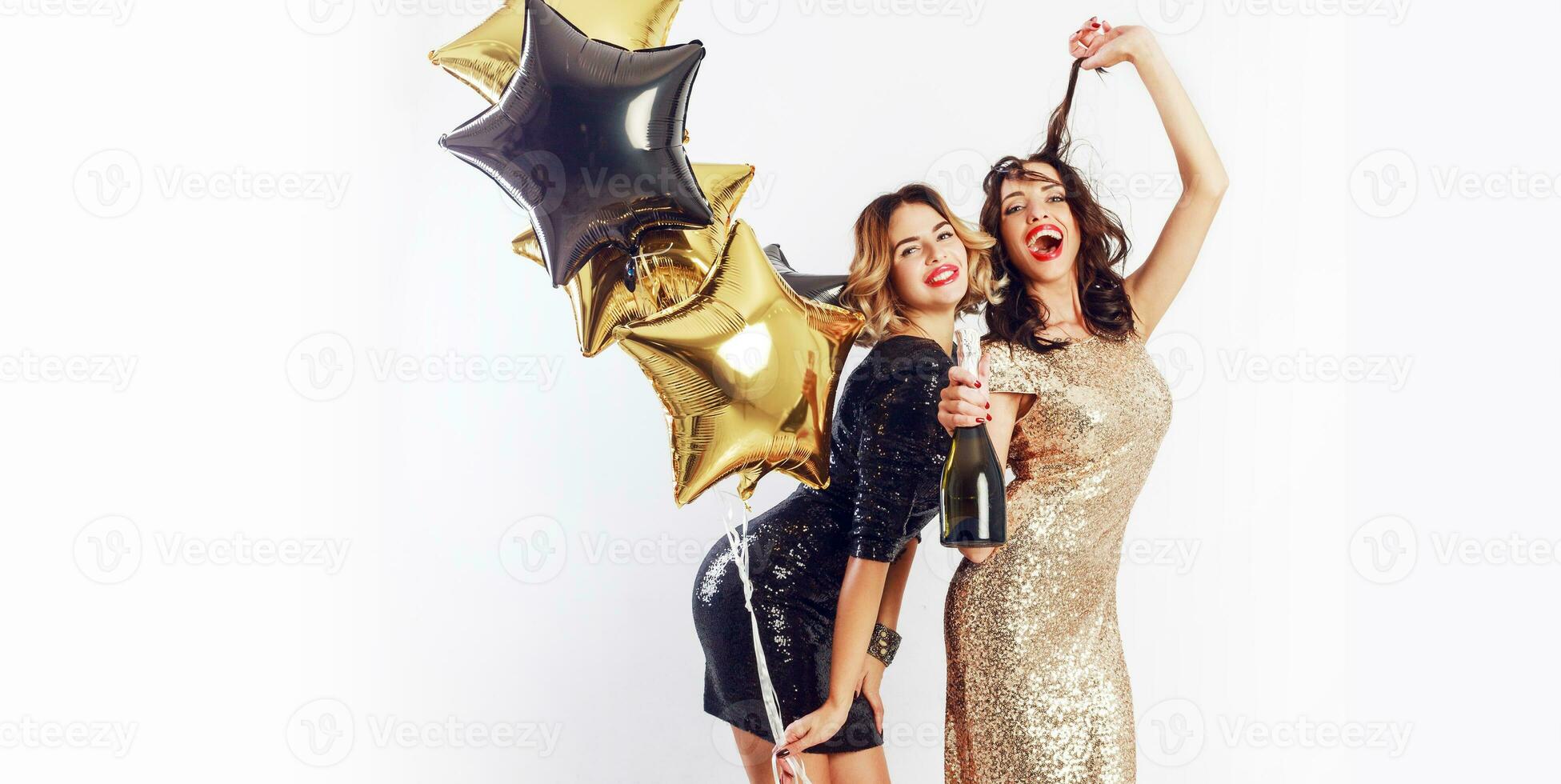 schließen oben positiv Studio Bild von zwei tolle sexy feiern Frau mit rot Lippen, Lachen , posieren auf Weiß Hintergrund. halten Flasche von Champagner , haben Spaß. foto