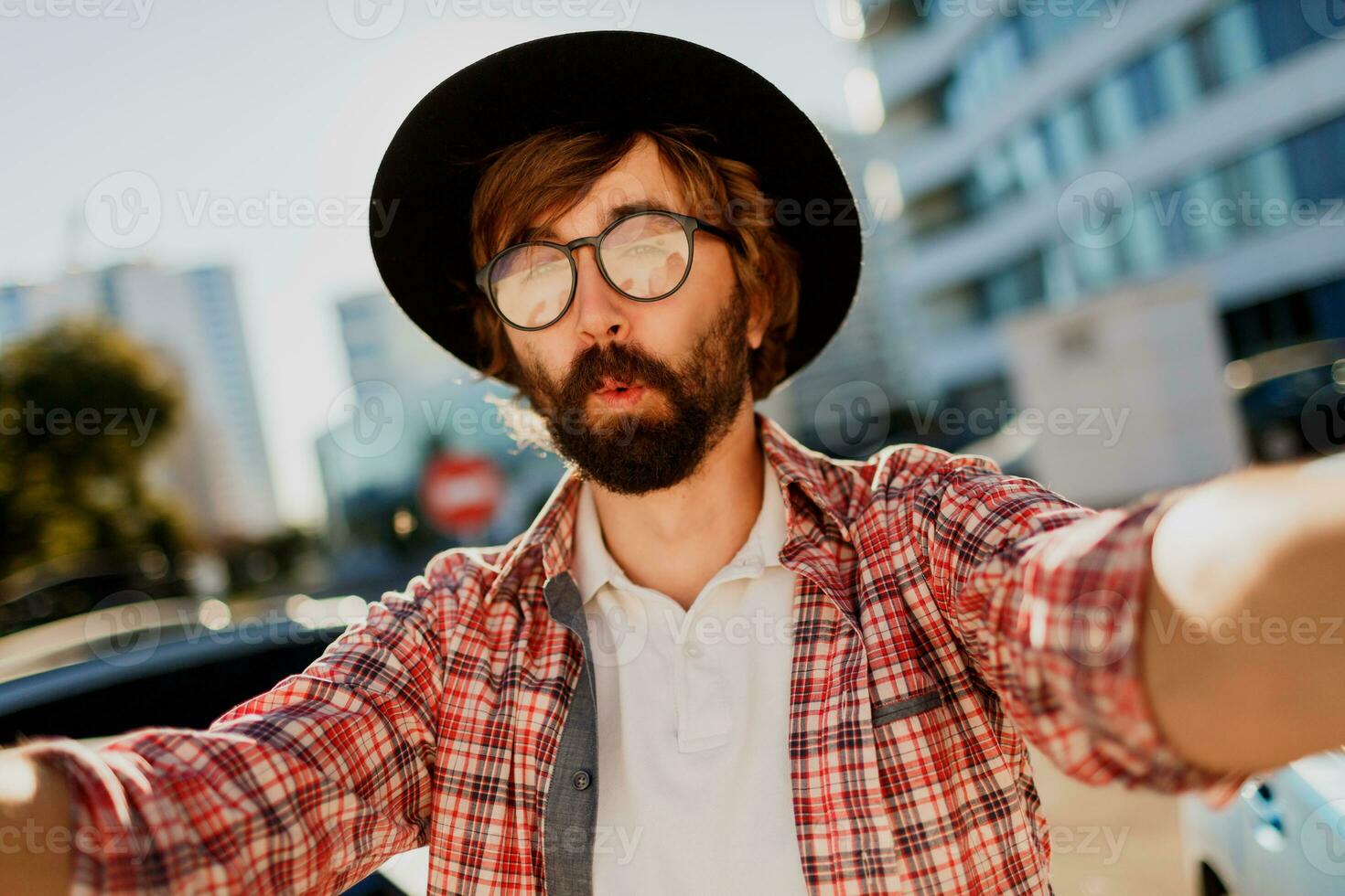 komisch Mann mit Bart Herstellung selbst Porträt durch Kamera während er Reisen im groß modern Stadt im Asien. foto