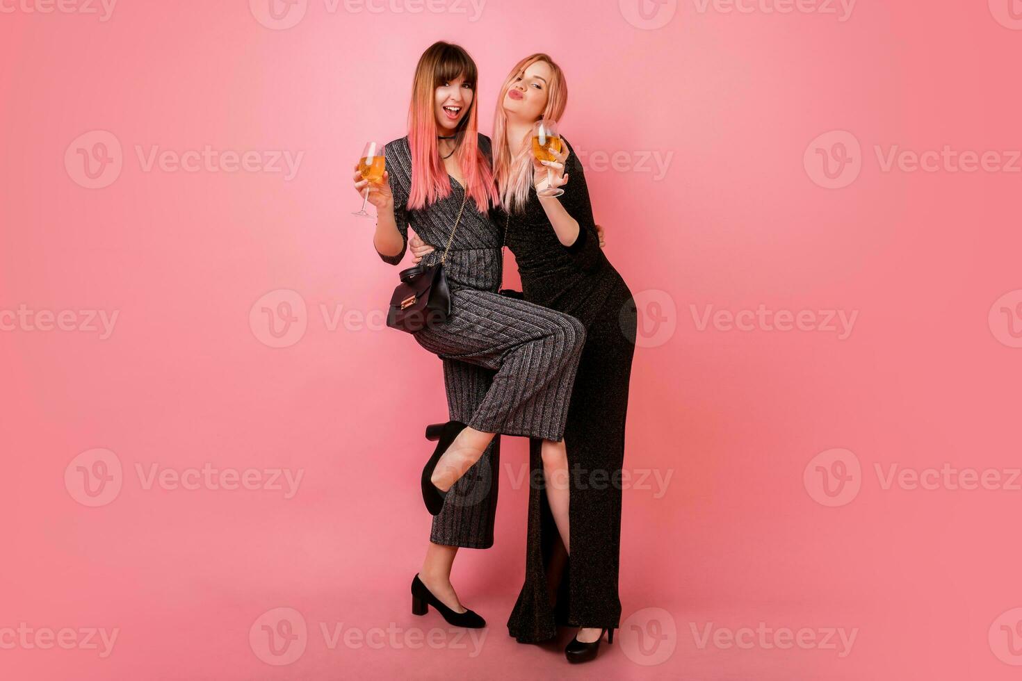 voll Länge Studio Bild von feiern Frauen im Party Kleid Trinken Champagner und haben großartig Zeit zusammen. Rosa Hintergrund. glücklich Emotionen. foto