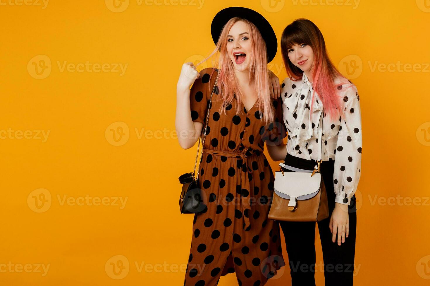 ziemlich Mädchen Gehen und haben Spaß auf Gelb Hintergrund im Studio. glücklich Frau mit Rosa Haare mit ihr blond Freund haben großartig Zeit. foto