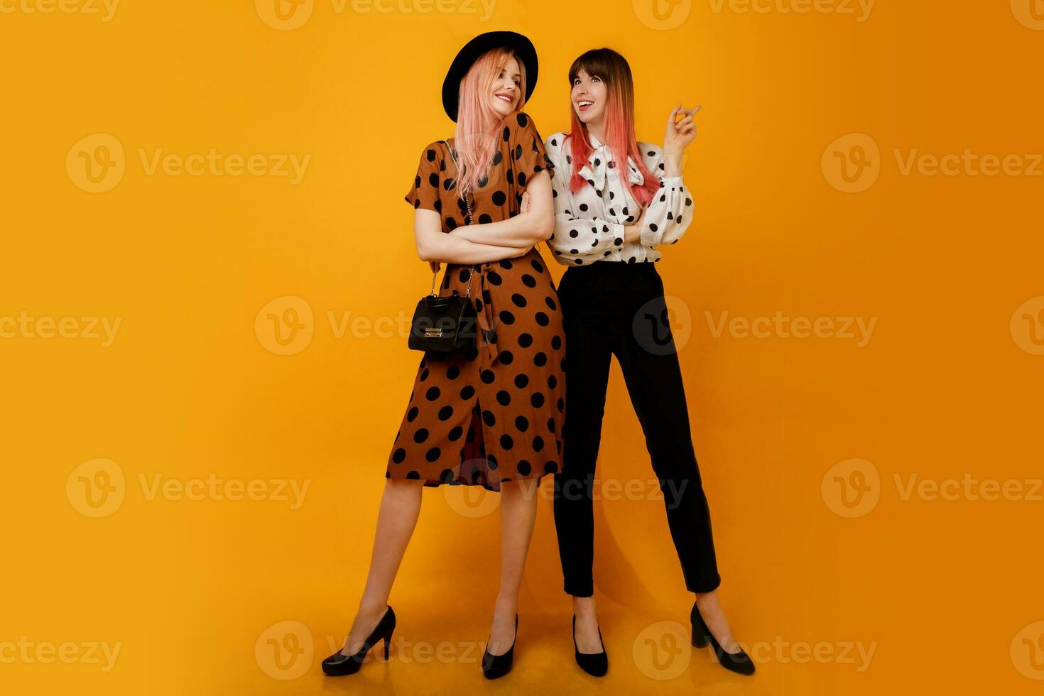 in voller Länge Studio Bild von stilvoll Frauen im Kleid posieren Über Gelb Hintergrund. froh weiblich Modelle im stilvoll Kleidung. Einkaufen und Mode Konzept. foto