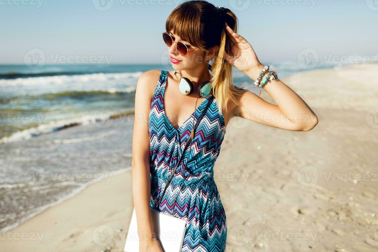 ziemlich Reisender Frau mit Tablette ob sonnig Strand, Zuhören Musik, gehen, genießen Feiertage. Sommer- Stimmung. foto