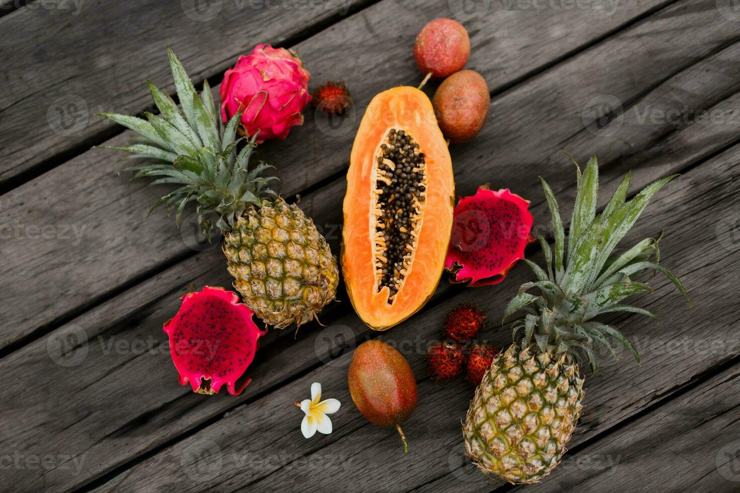 kreativ Komposition mit tropisch Früchte auf Holz Hintergrund, oben Sicht. Scheiben von Papaya, Drachen Obst und Ananas. foto