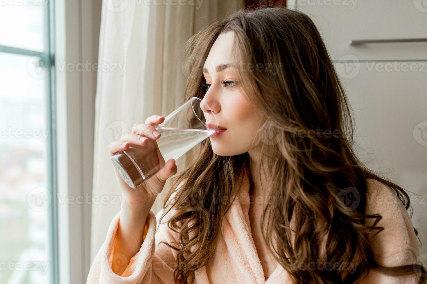 ziemlich Frau im Bademantel Trinken frisch Wasser beim Zuhause . foto
