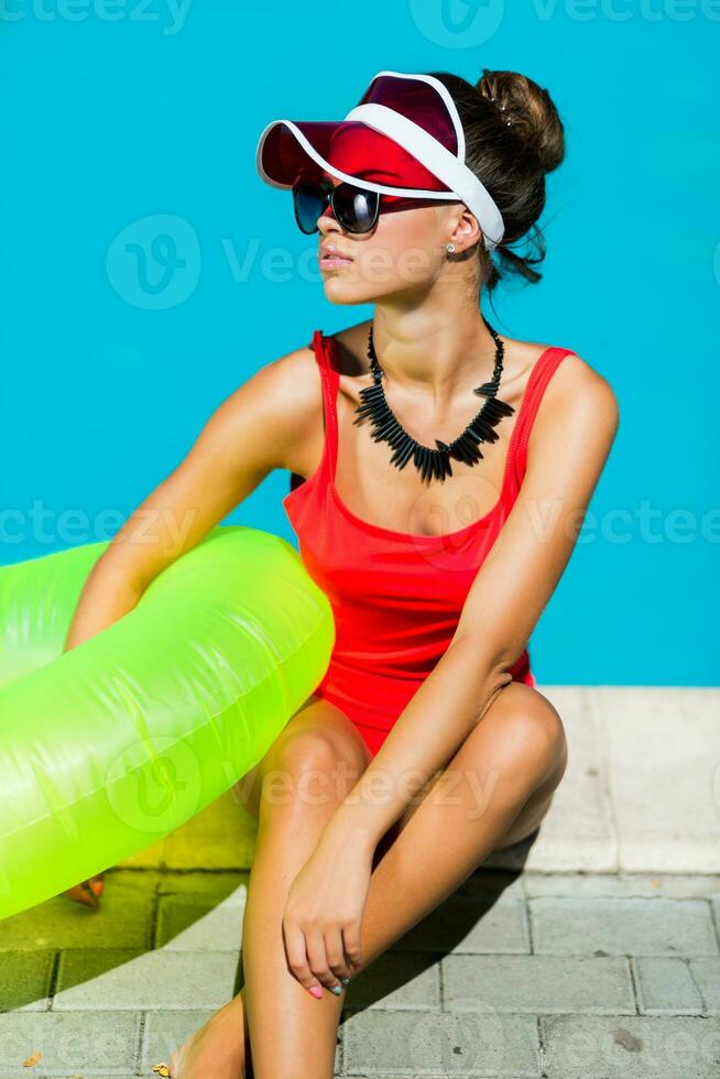 sexy Braun gebrannt Frau im rot Badeanzug haben Spaß und genießen Sommer- im tolle groß Schwimmen Schwimmbad. stilvoll transparent Deckel. Strand Party. foto