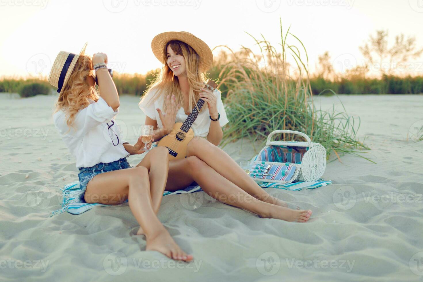 Beste Freunde, zwei sorglos Mädchen genießen Strand Party und Trinken Cocktails. Sommer- Feiertage. Picknick Korb auf Hintergrund . foto
