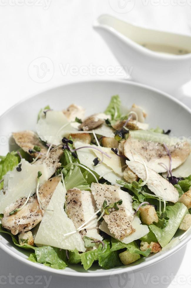 Bio-Hähnchen-Caesar-Salat mit Parmesan und Croutons auf weißem Tischhintergrund foto