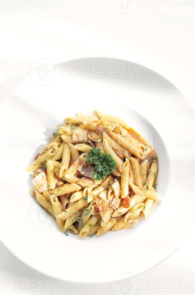 Penne amatriciana Bio-Tomaten-Schinken-Sauce-Nudelgericht auf weißem Tisch foto