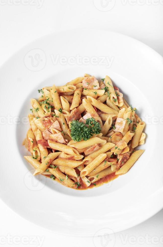 Penne amatriciana Bio-Tomaten-Schinken-Sauce-Nudelgericht auf weißem Tisch foto