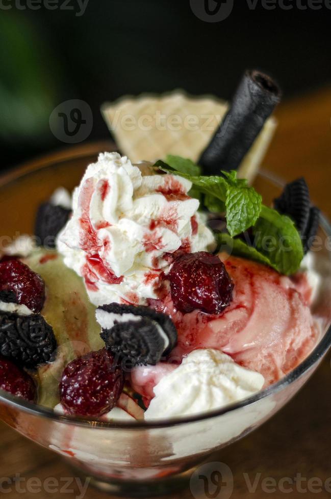 Himbeer-Pistazien-Eisbecher Dessert in Glasschale mit Schokoladenkeksen und Beeren foto