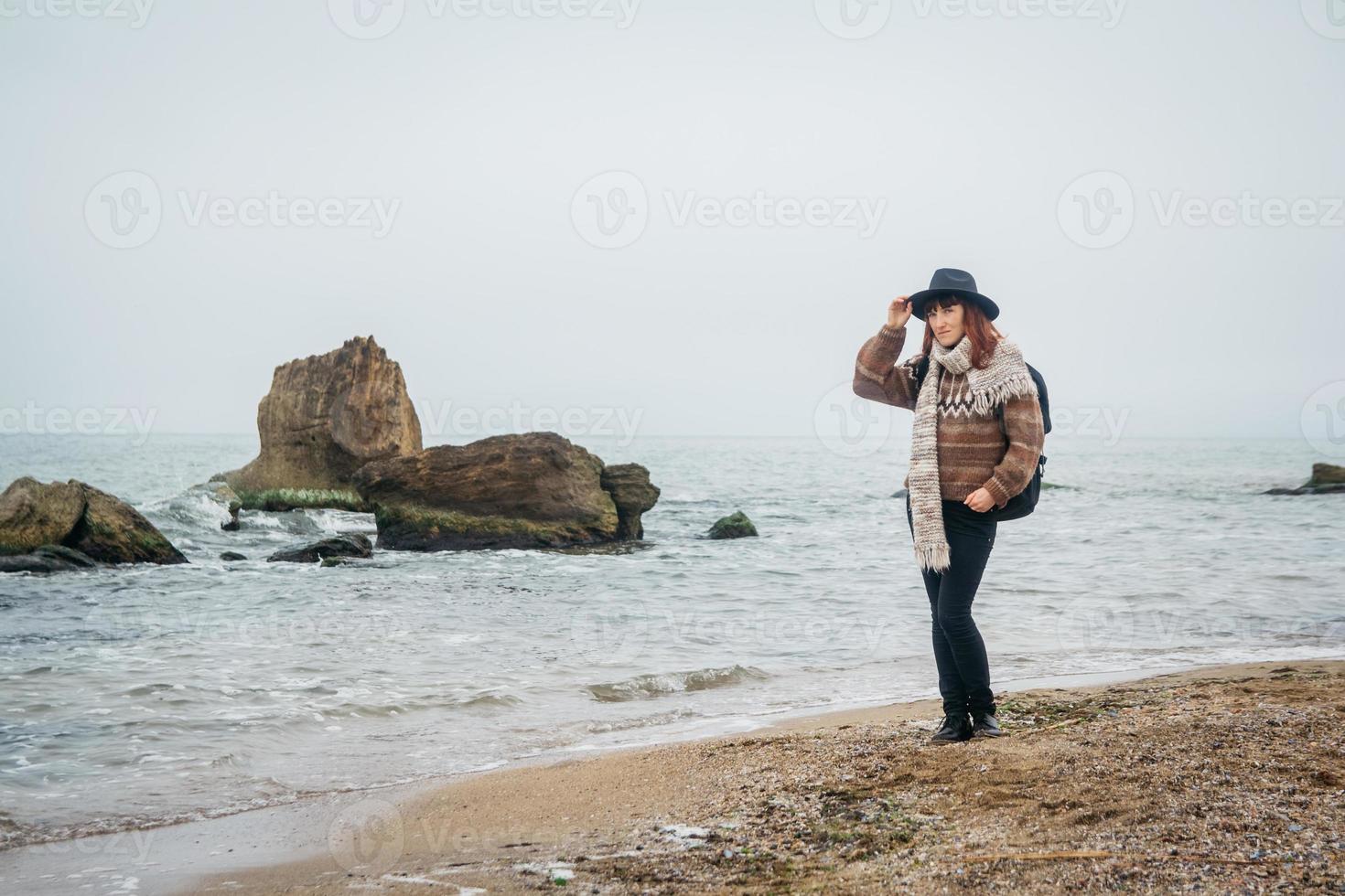 Frau mit Hut und Rucksack am Strand vor dem Hintergrund des Meeres foto