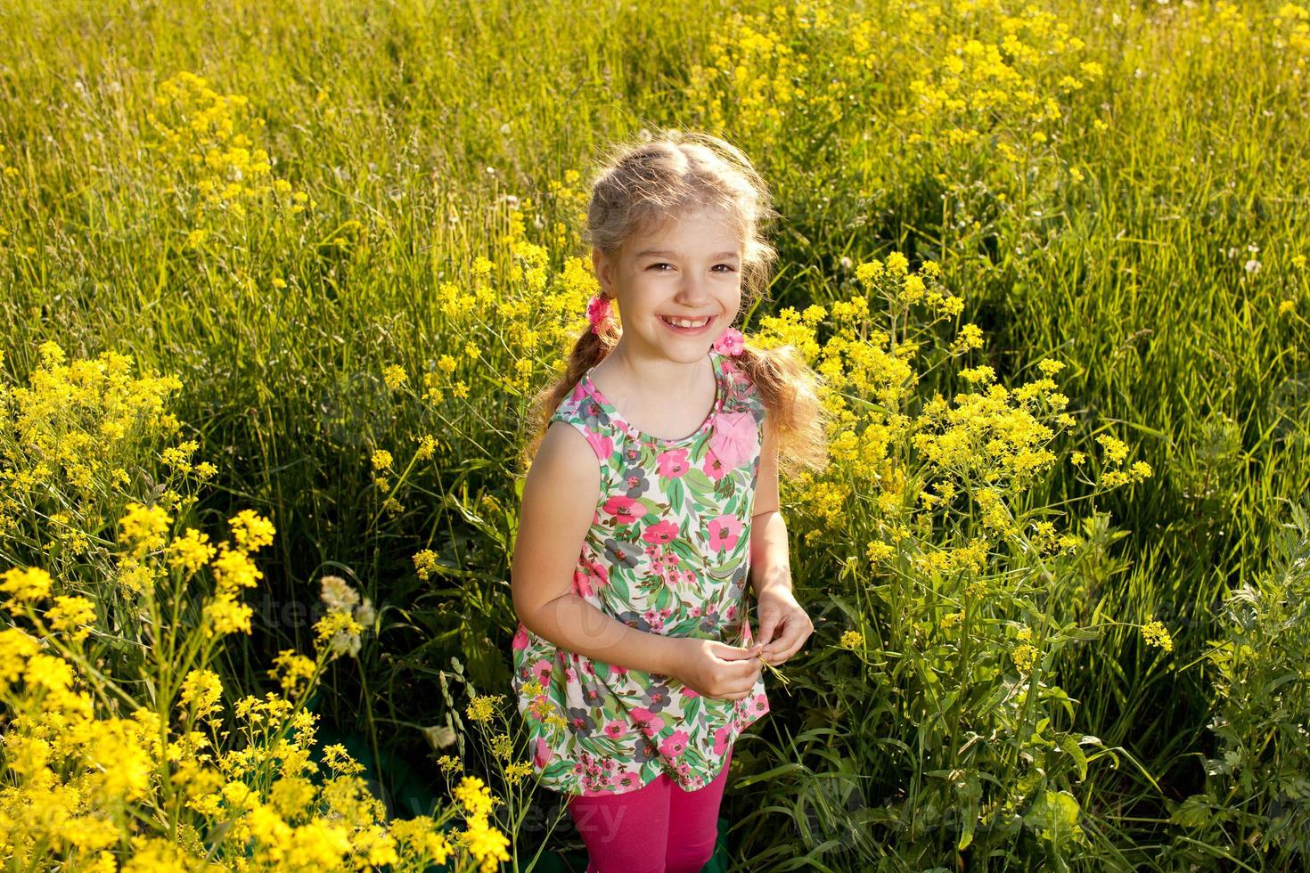 lustiges kleines Mädchen unter gelben Wildblumen foto