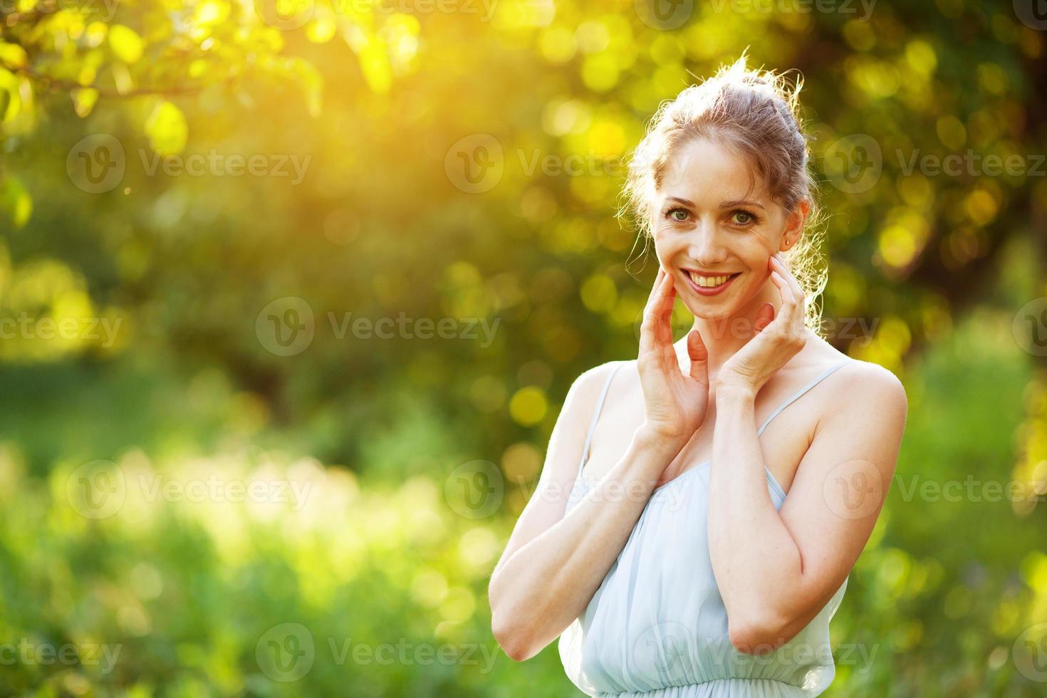 fröhliche junge Frau in einem Kleid in den Strahlen der Abendsonne foto