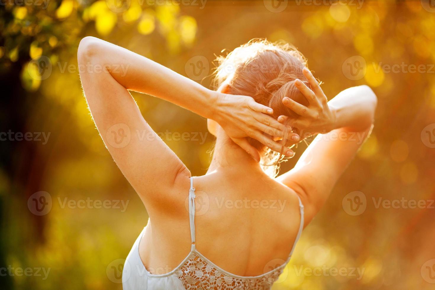 junge Frau im Kleid in den Strahlen der Sonne foto