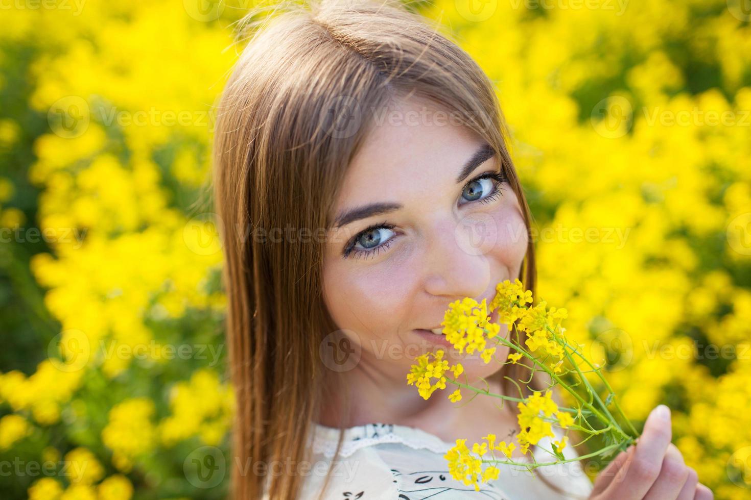 fröhliches Mädchen, das gelbe Wildblumen riecht foto