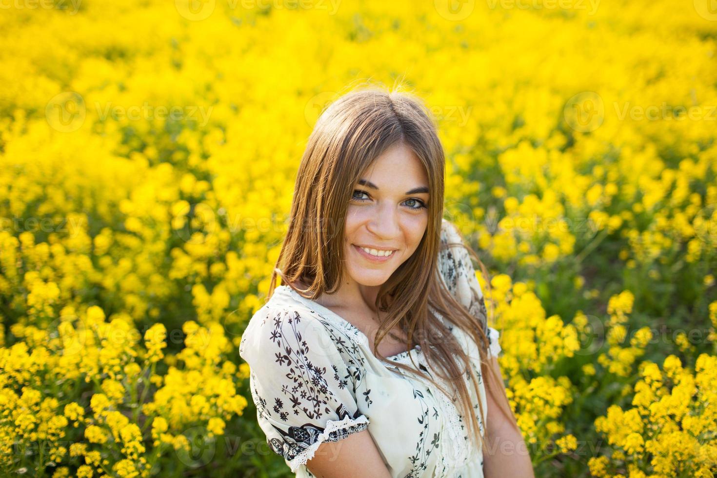 schöne Frau zwischen gelben Blumen auf einem Feld foto