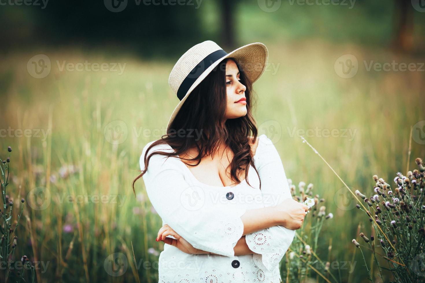 schöne Frau mit Strohhut im Gras des Feldes foto