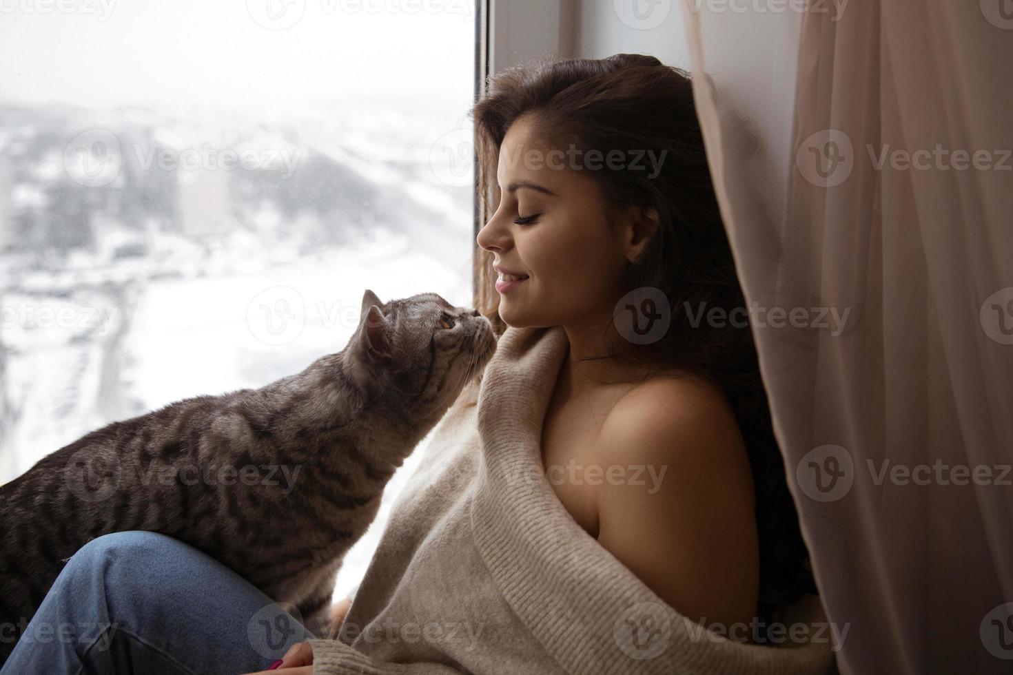 Mädchen und eine große Katze am Fenster foto