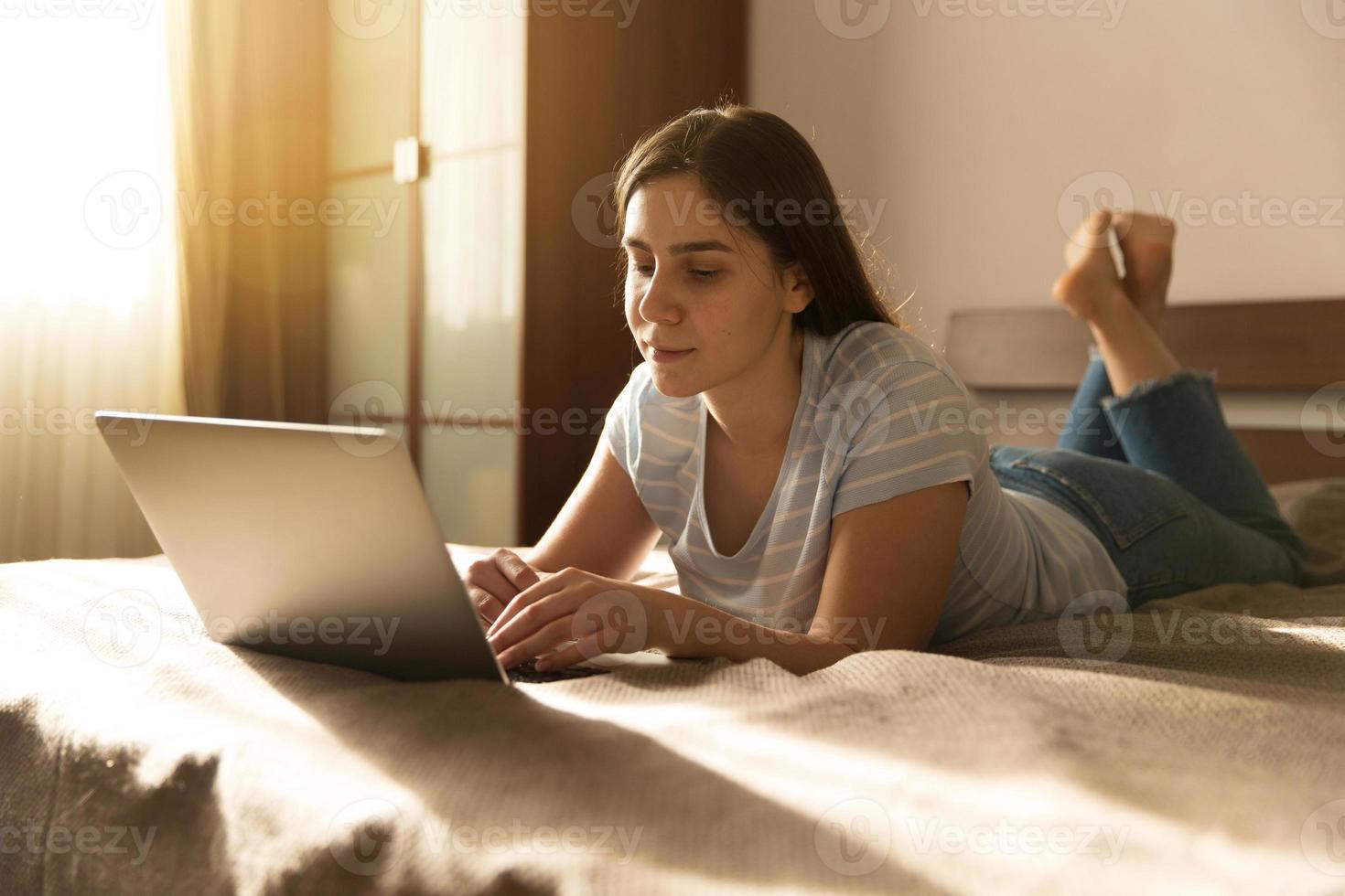 Mädchen liegt vor einem Laptop foto