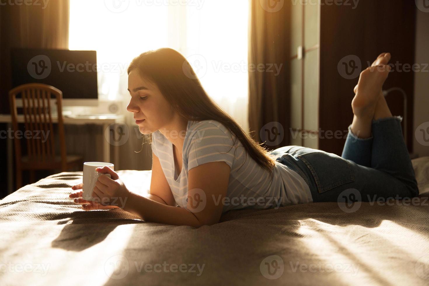 junge Frau liegt mit einer Tasse Kaffee foto