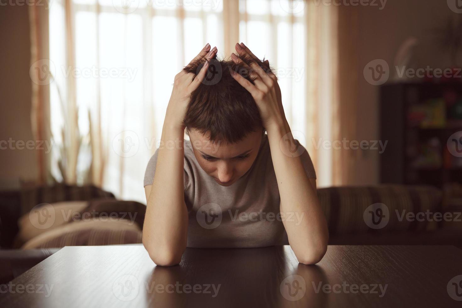 junge Frau sitzt und umarmt ihren Kopf foto