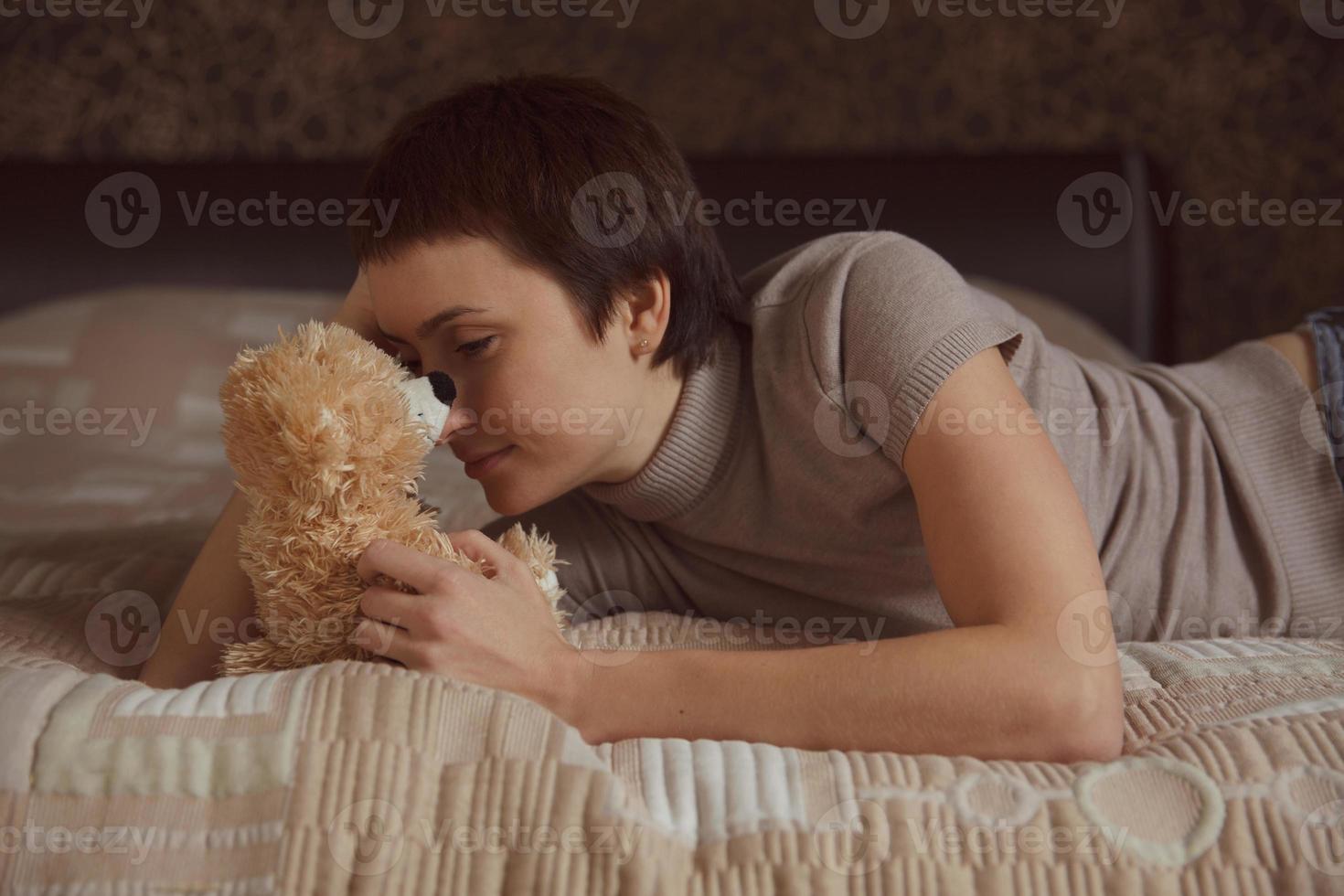 Mädchen liegt mit einem Teddybären auf dem Bett foto