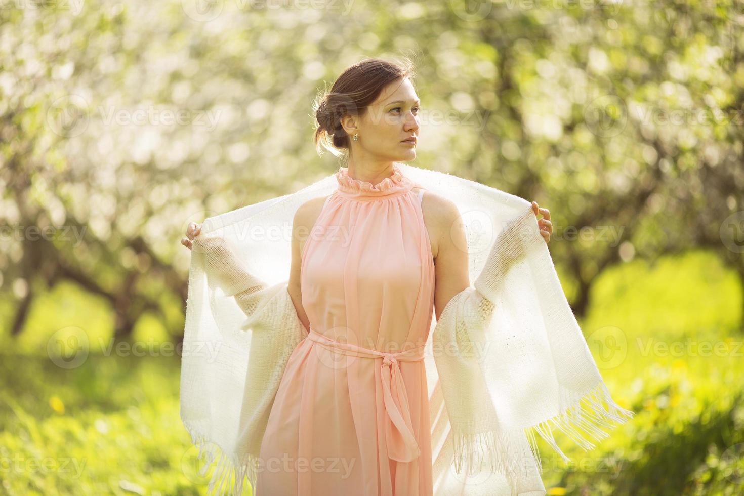 Mädchen in Kleid und Schal im Apfelgarten foto