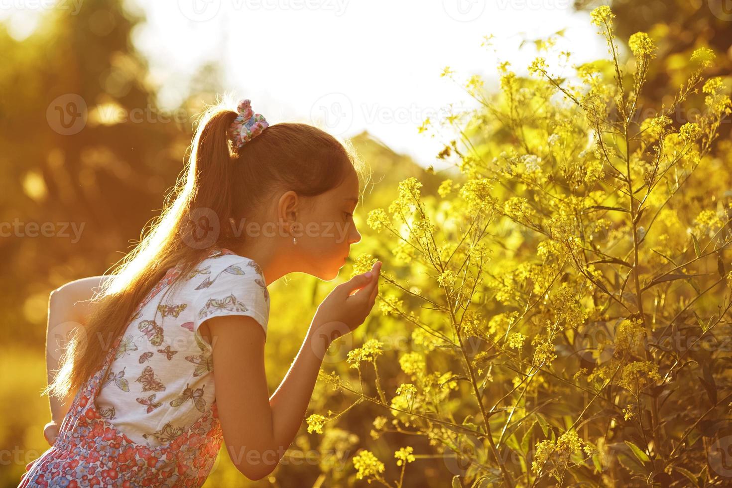 kleines Mädchen, das an einer gelben Blume schnüffelt foto