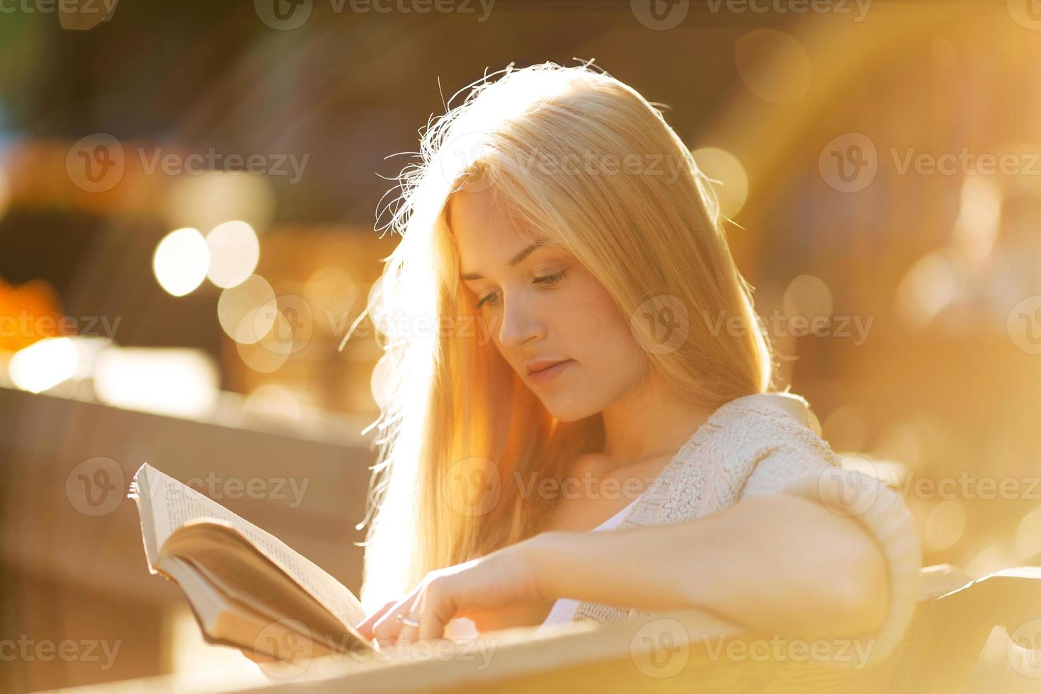 glückliches blondes Mädchen, das ein Buch liest foto