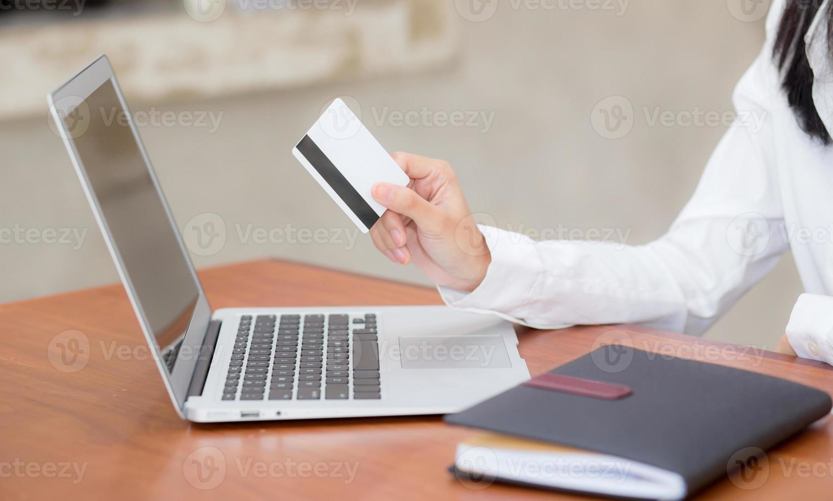 junge asiatische frau, die eine kreditkarte hält und online einkauft. foto