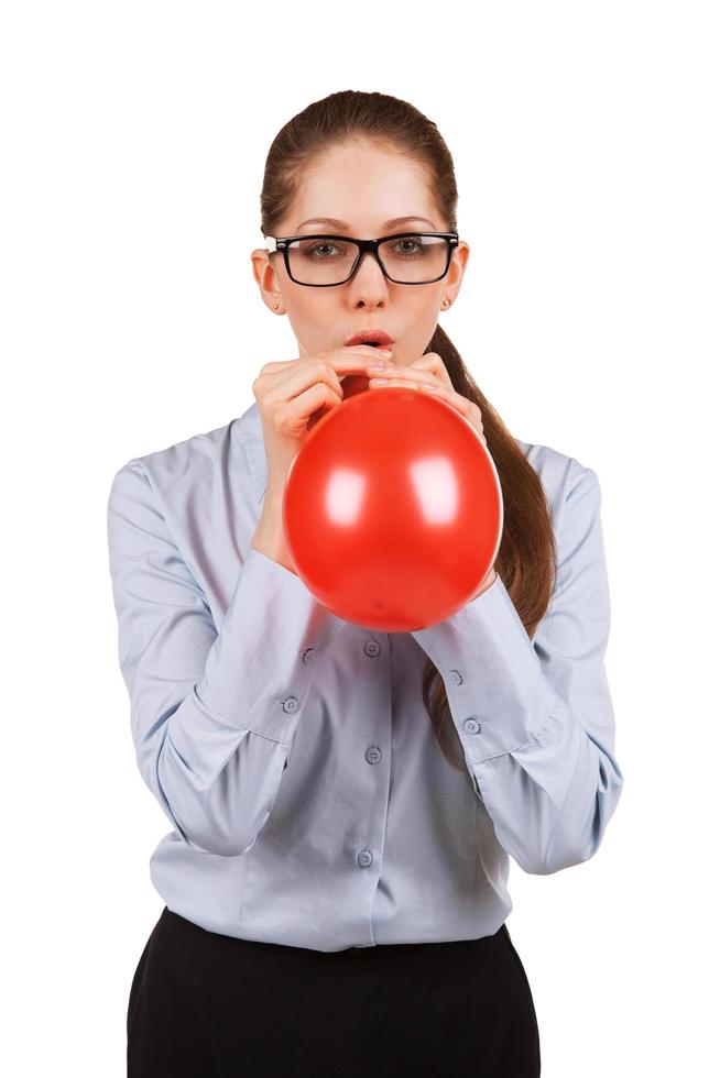 Mädchen mit Brille, das einen roten Ball aufbläst foto