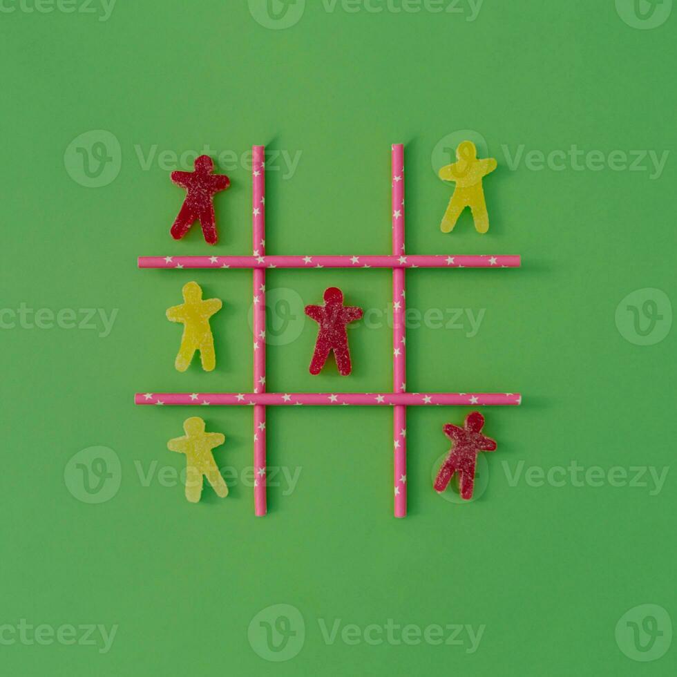 Tic-Tac-Toe, Nullen und Kreuze oder xs und os Spiel gemacht mit gummiartig Süßigkeiten und Strohhalme auf Pastell- Grün Hintergrund. komisch kreativ Idee. minimal Layout. foto