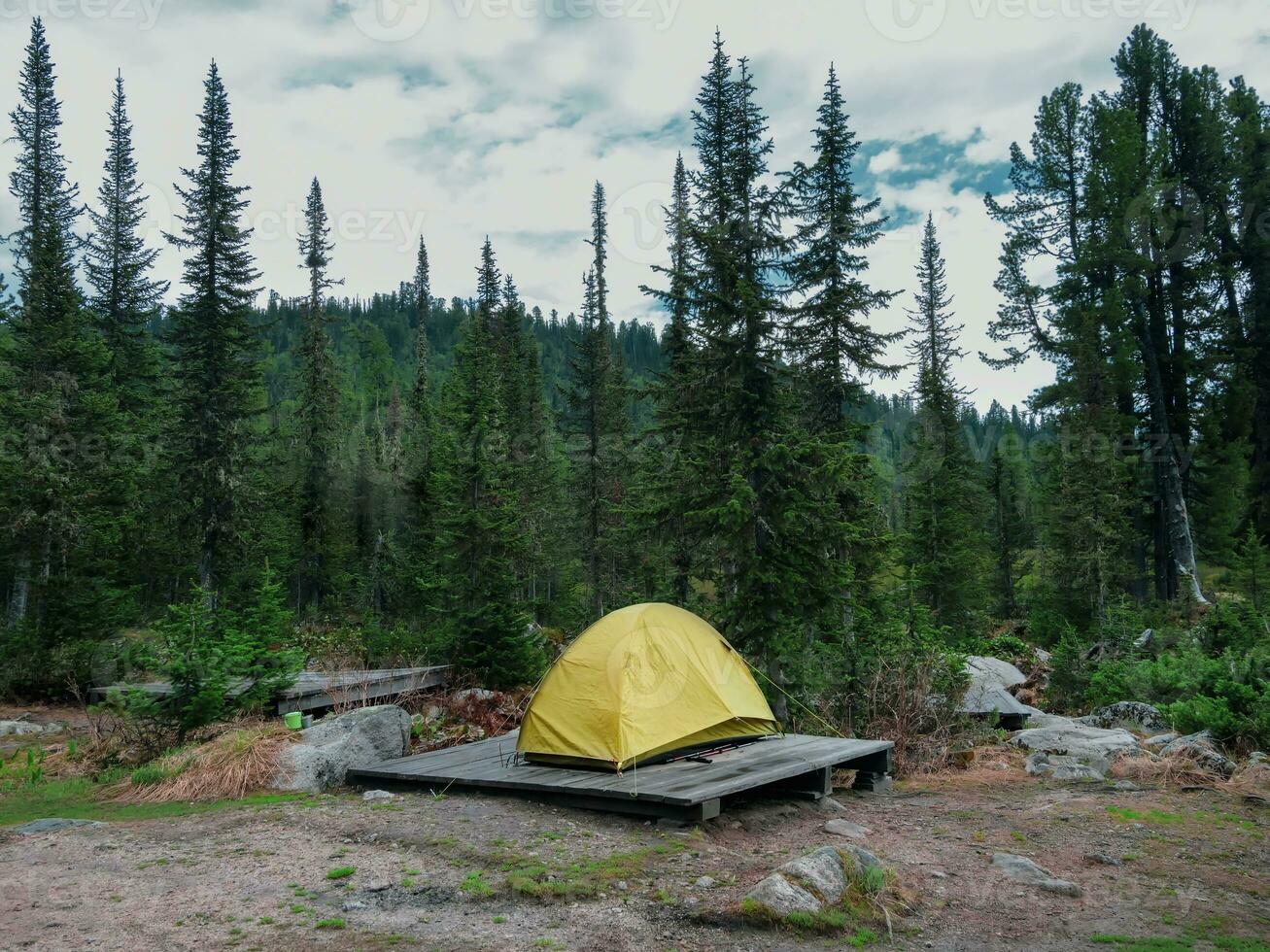 Zelt Camping im das Taiga, ein Single Zelt auf ein hölzern Sockel im das Abend. Schlecht Wetter auf ein Wanderung, Camping im das Regen. Camping Leben Konzept. foto