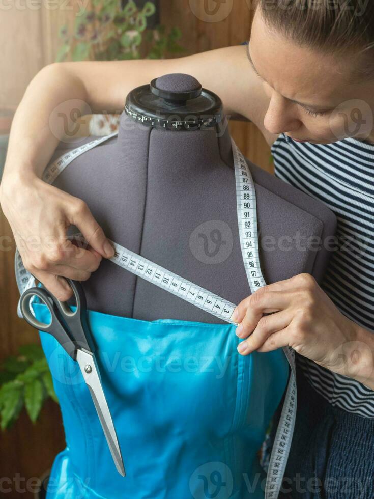 Nahansicht von Arbeit Prozess von ein Schneider im ihr Studio. Hände mit Schere messen das Hochzeit Kleid im das Prozess von Nähen. foto