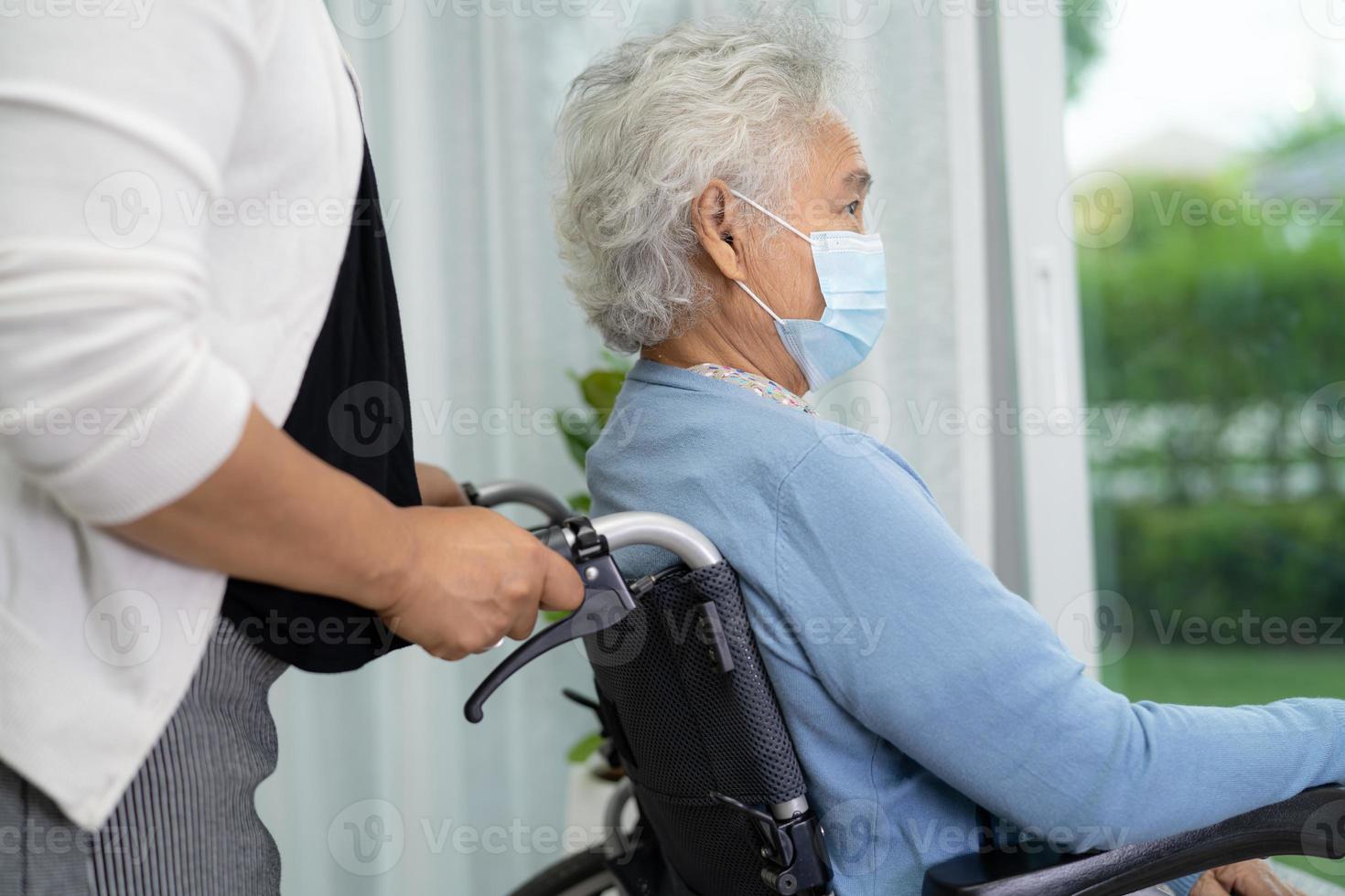 Helfen Sie asiatischen Senioren, die im Rollstuhl sitzen und eine Maske tragen, um das Coronavirus zu schützen. foto