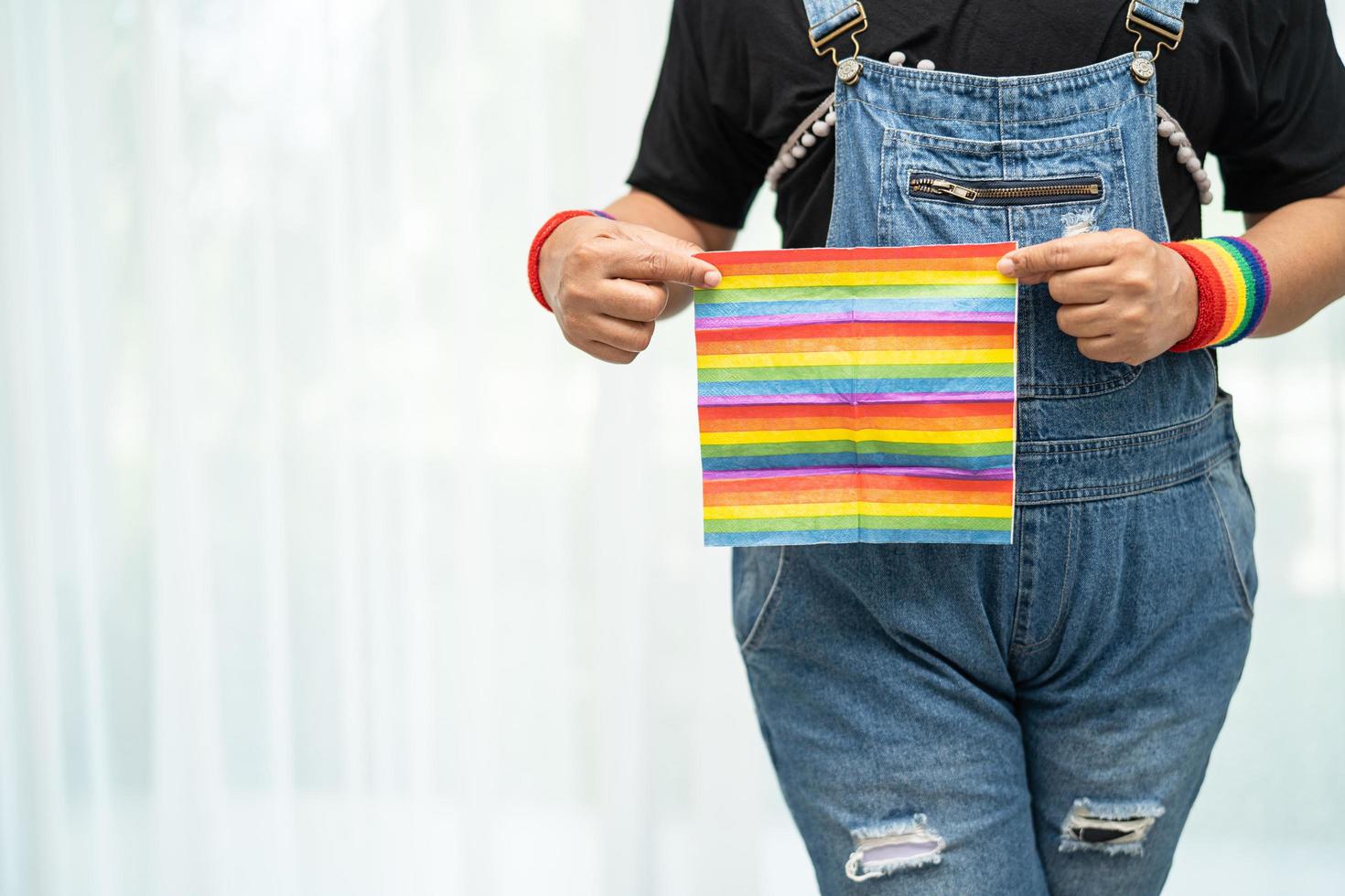 asiatische dame mit regenbogenfarbener flagge, symbol des lgbt-stolz-monats foto