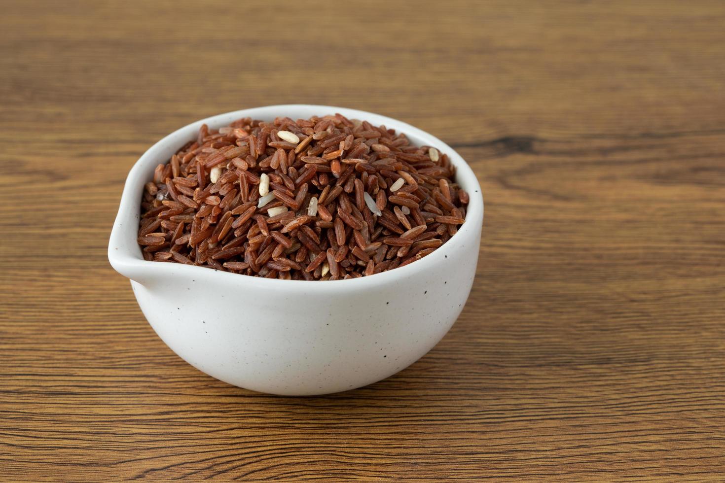brauner Reis für gesunde weiße Schüssel auf Holzhintergrund foto