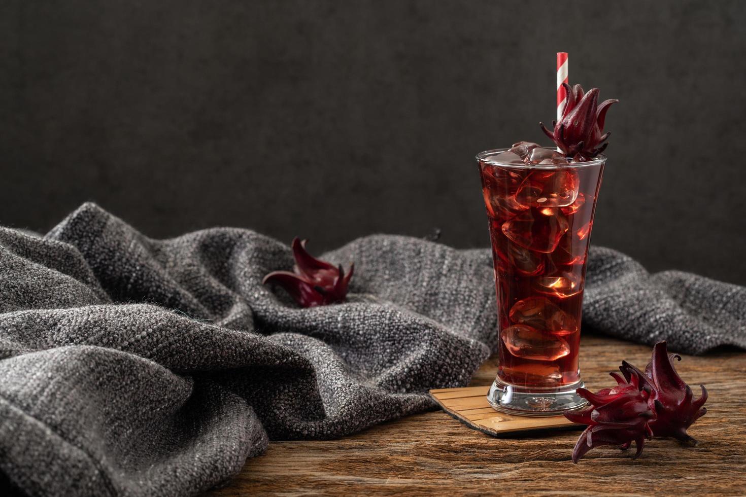 Roselle Klarglas mit frischen Roselle Früchten auf Holztisch foto