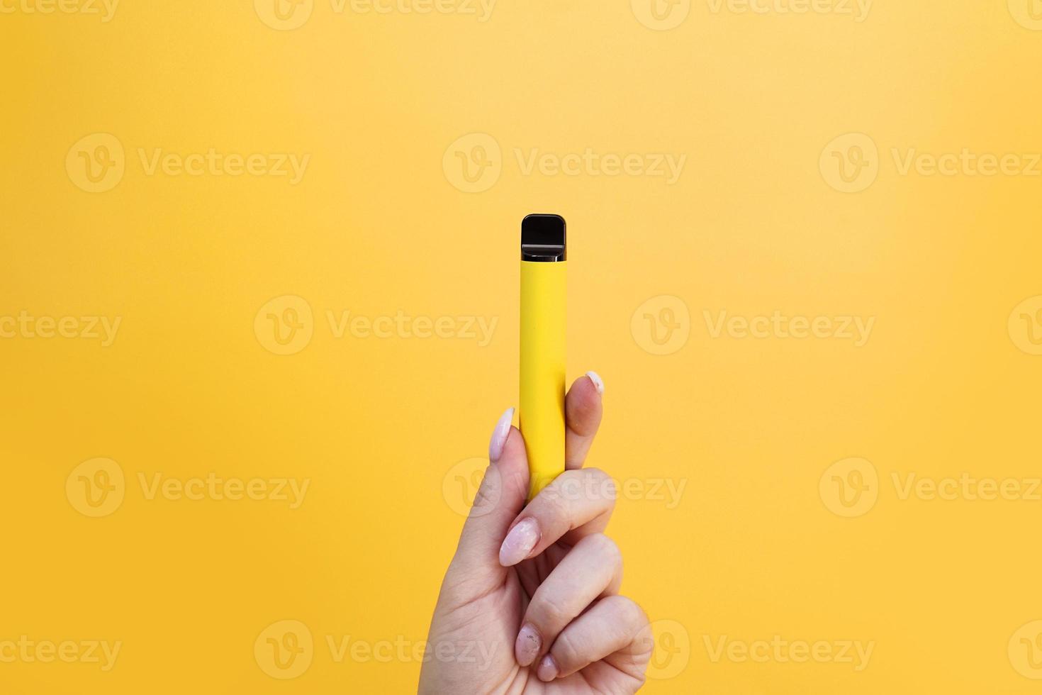 gelbe elektronische Einwegzigarette in weiblicher Hand foto