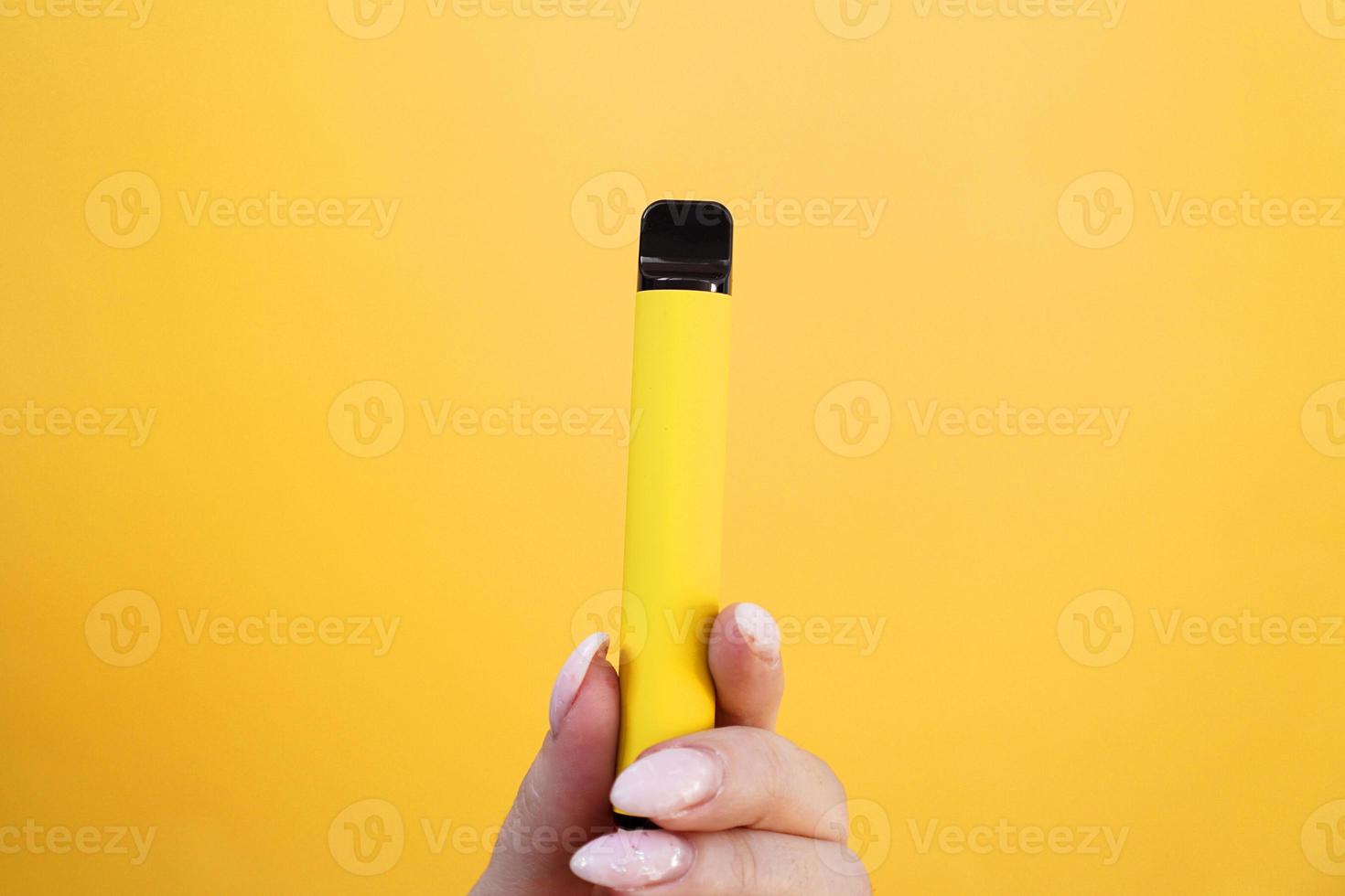 gelbe elektronische Einwegzigarette in weiblicher Hand foto