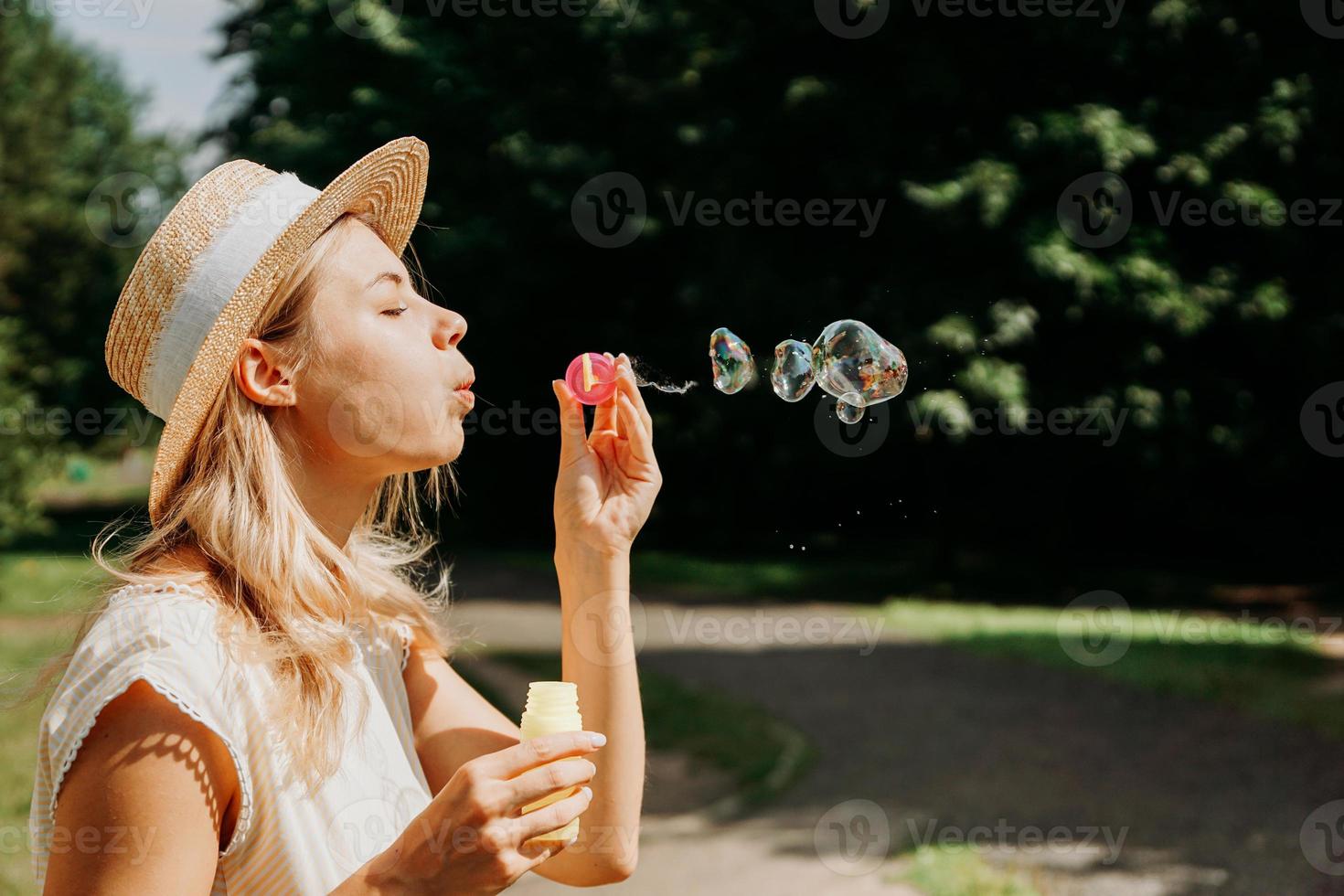 süße blonde Frau bläst Seifenblasen. schöner grüner park foto