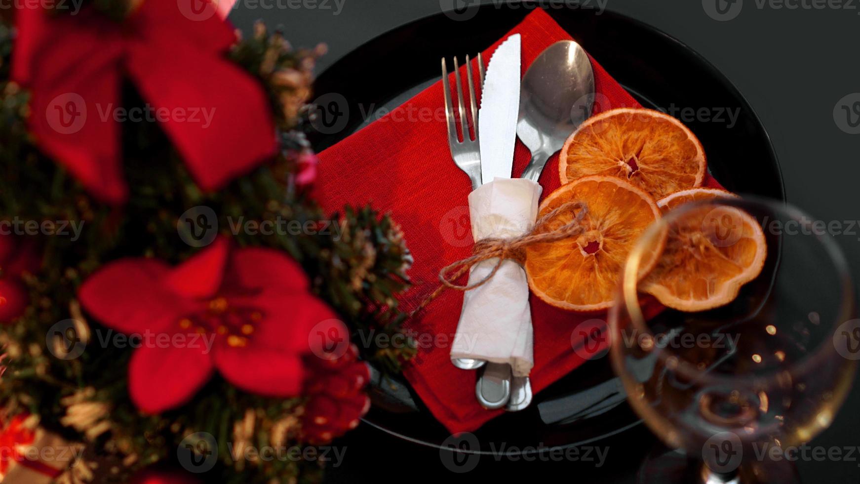 Einstellung für festliches Weihnachtsessen auf schwarzem Tisch mit Dekoration foto