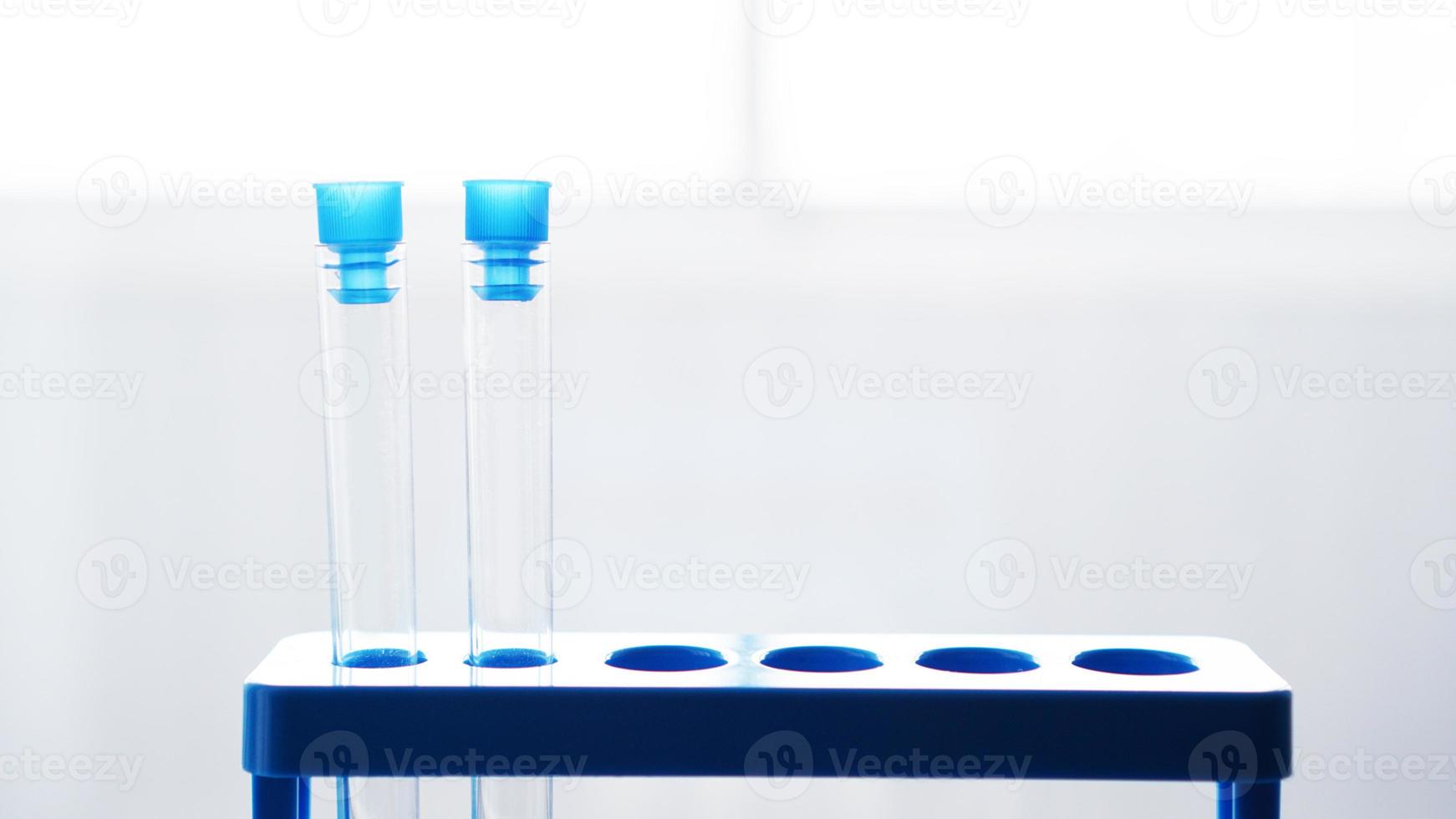 Reagenzgläser auf blauem Ständer auf verschwommenem grauem Hintergrund foto