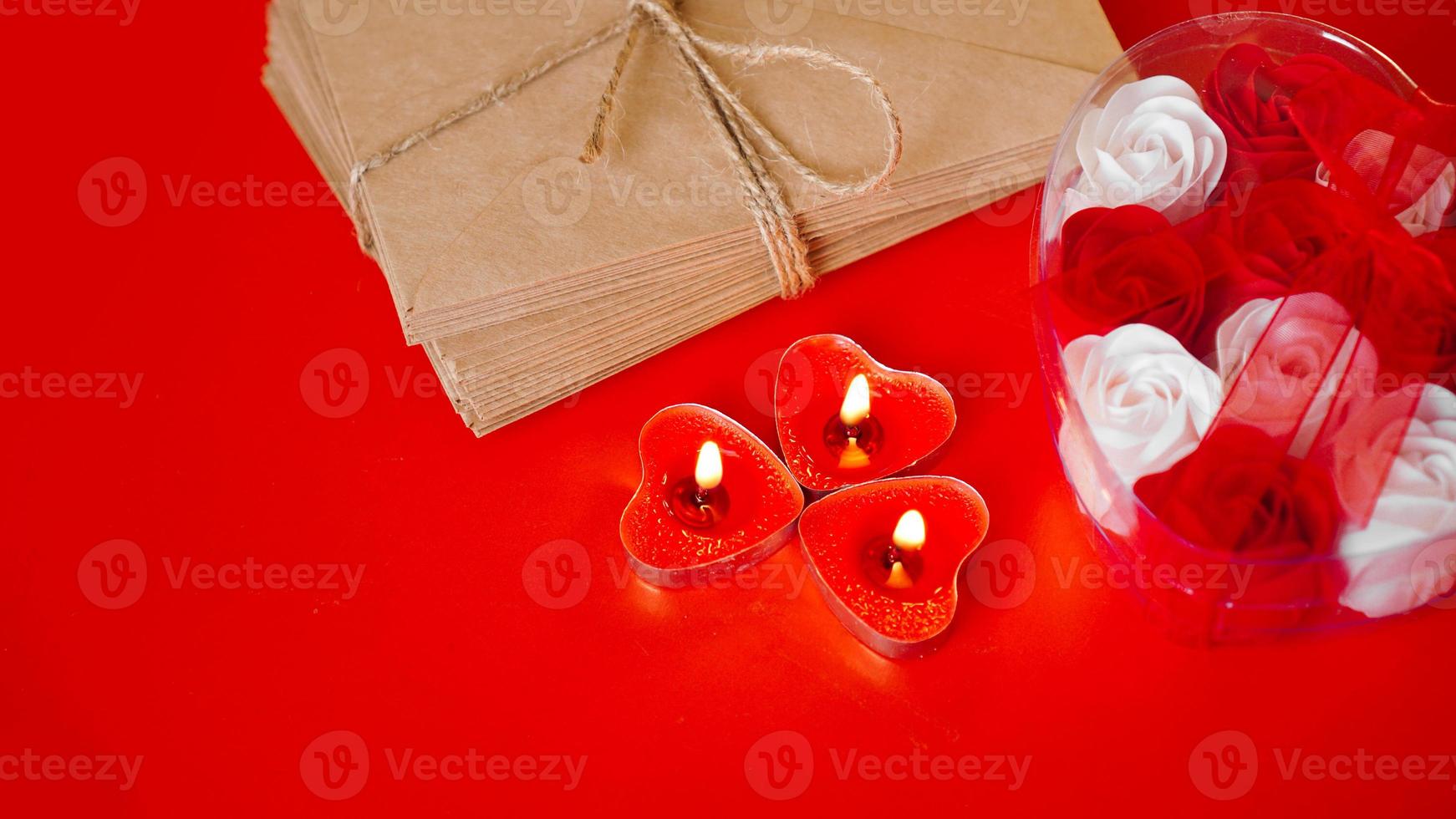 Kraftpapierumschläge mit roten Kerzen auf rotem Grund. foto