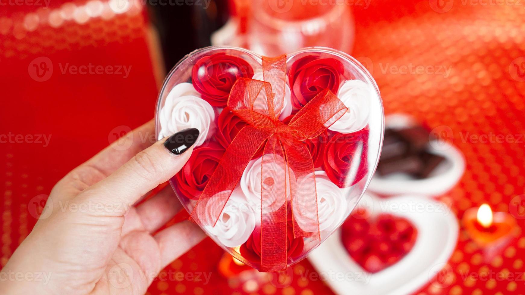 Frauenhände halten eine Geschenkbox in Herzform mit schöner Rose foto