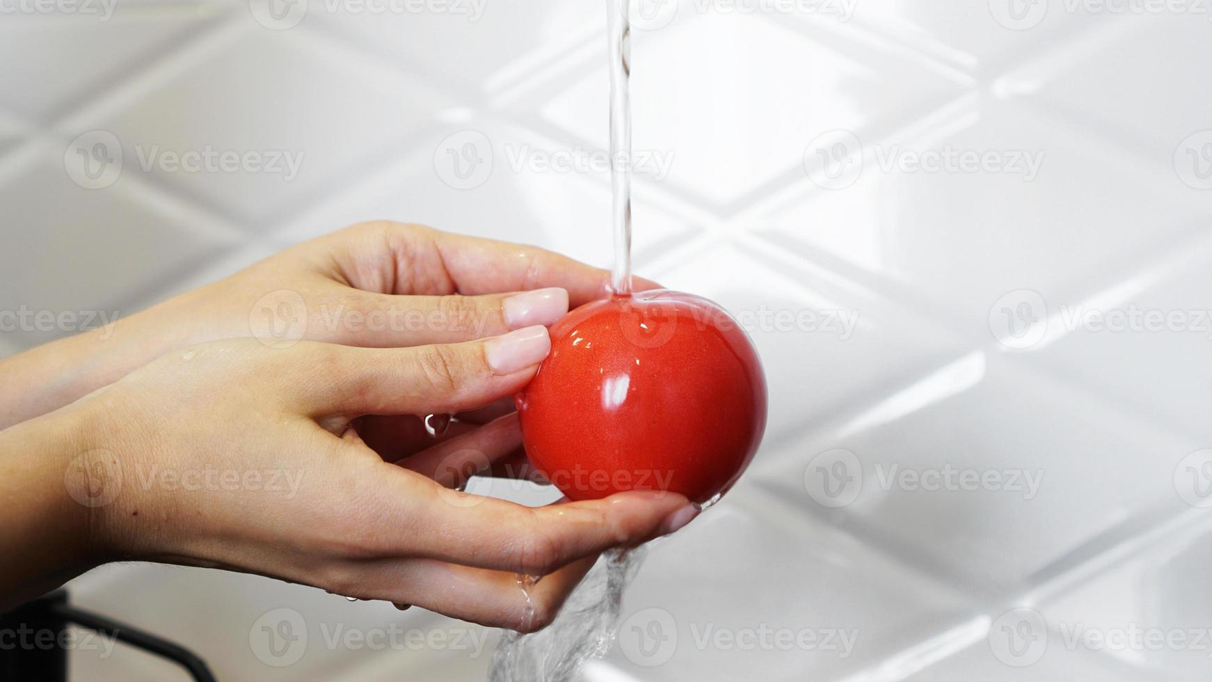 Frau wäscht Tomaten und Tomaten in ihren Händen foto