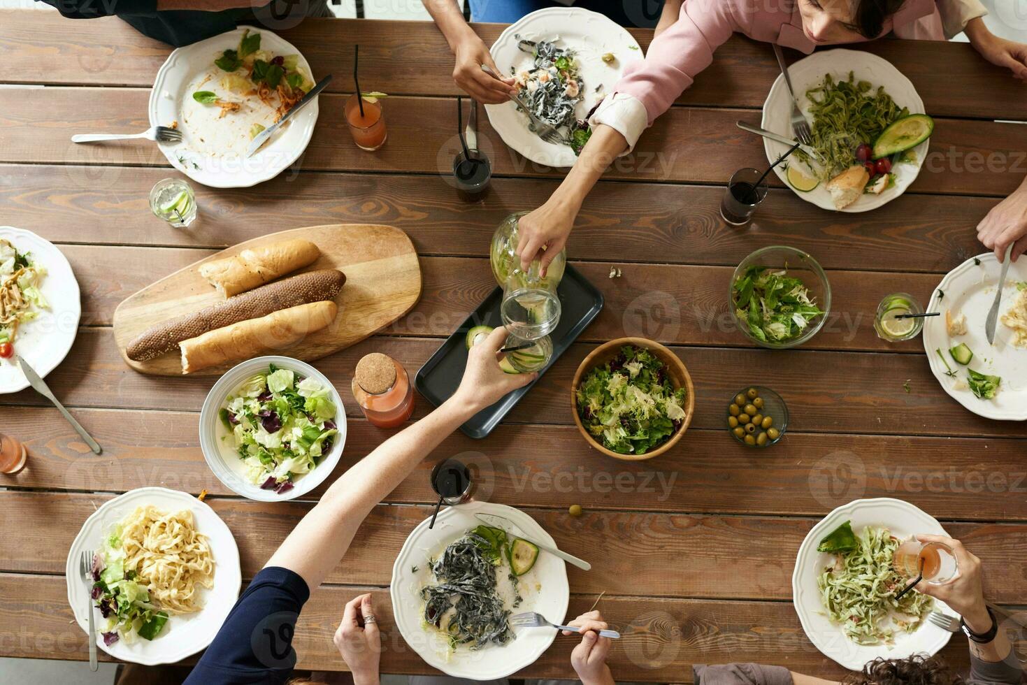 oben Aussicht von Gruppe von Menschen haben Abendessen zusammen während Sitzung beim hölzern Tabelle foto