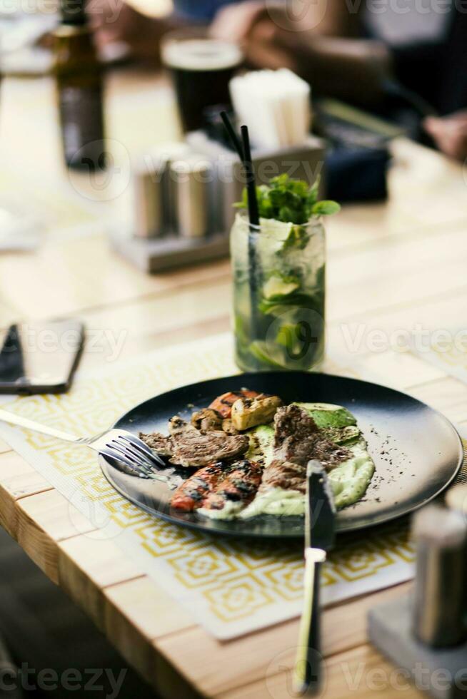 gegrillt Kebab auf ein schwarz Teller auf ein hölzern Tabelle foto