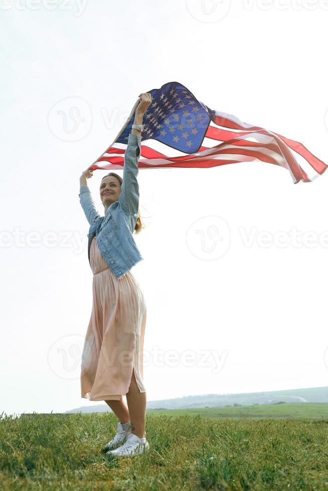 ein mädchen in einem korallenkleid und einer jeansjacke hält die flagge von usa foto