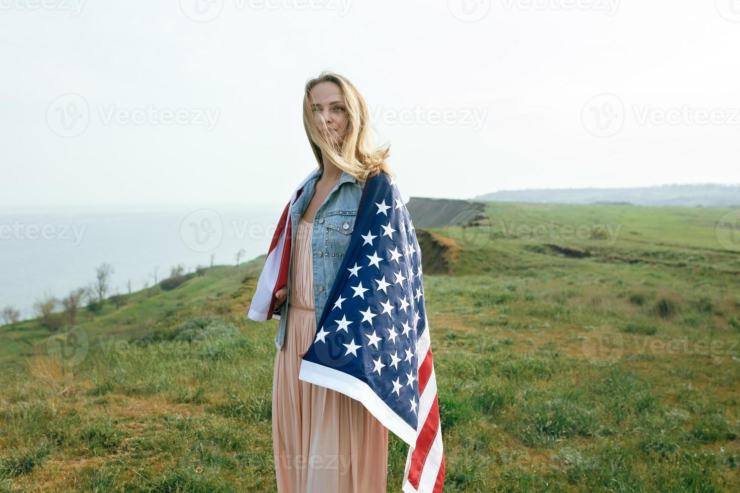 ein mädchen in einem korallenkleid und einer jeansjacke hält die flagge von usa foto